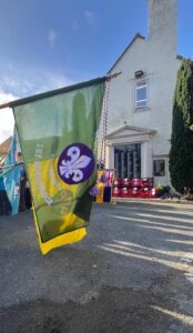 Scout flag being held in front of war memorial with re poppy wreaths