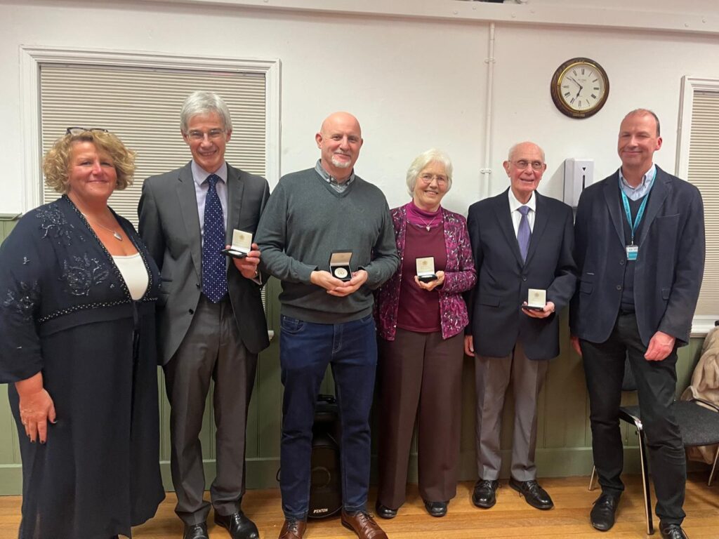 six people standing in a line with four in the middle holding civic medallions