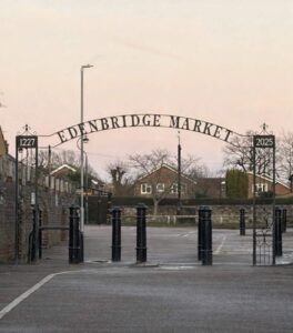 Empty car park with iron archway with words Edenbridge Market
