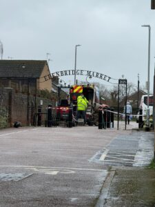iron archway with words Edenbridge Market with work van and men in high visability jackets