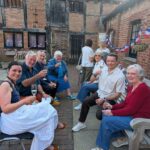 Group of people sitting on outdoor bench raising a glass of wine