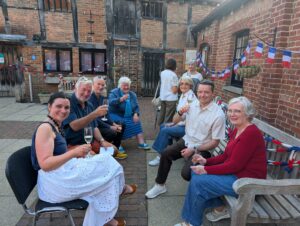 Group of people sitting on outdoor bench raising a glass of wine