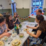 People sitting around a table eating with French flags in the background