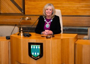 Lady councillor wearing civic chain of office siting at chairman's desk
