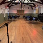 Interior of hall with wooden floor, tables and chairs and bunting