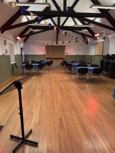 Interior of hall with wooden floor, tables and chairs and bunting