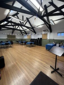 Interior of hall with wooden floor, tables and chairs and bunting