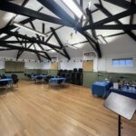 Interior of hall with wooden floor, tables and chairs and bunting