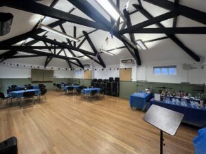 Interior of hall with wooden floor, tables and chairs and bunting