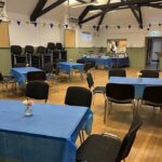 Interior of hall with wooden floor, tables and chairs and bunting