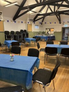 Interior of hall with wooden floor, tables and chairs and bunting
