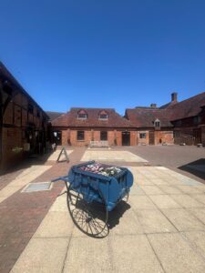 exterior of brick building with tiled roof, blue sky and flower cart in front of building