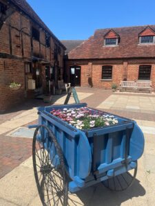 exterior of brick building with tiled roof in a courtyard with flower cart and blue sky