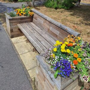 flowers in planter on end of wooden seat